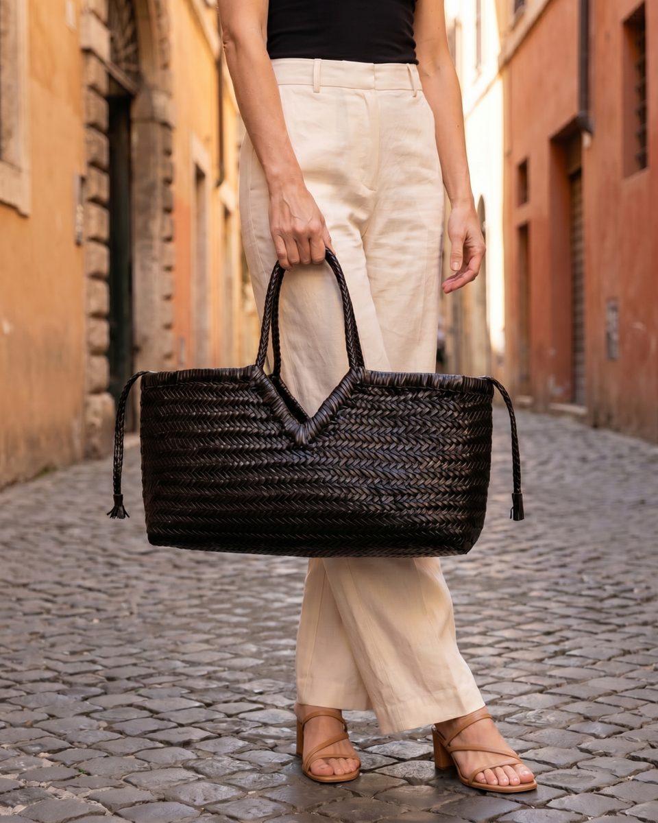 Close-up of a black handbag held on a cobblestone street